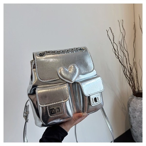 Detail view of silver metallic mini backpack with heart buckle and chain accents