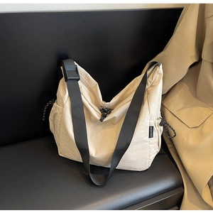 Detail of cream canvas messenger bag showing adjustable strap and brand label on side