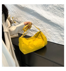 Detail van felgele crossbodytas met verstelbare riem en gekreukte nylon textuur