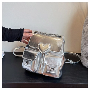 Detail of silver metallic mini backpack with 3D heart decor and metal twist locks