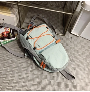 Dettaglio zaino outdoor leggero in nylon verde con cordini elastici arancioni e tasche