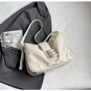 Detail of white patent leather underarm bag with three silver metal buckles on suit