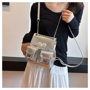 Detail of silver metallic bucket backpack with heart charm and chain straps