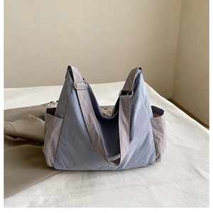 Detail view of large grey-blue and tan canvas crossbody bag with adjustable strap