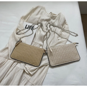 Detailed close-up of handmade woven straw bags in beige and coffee colors with silver chain