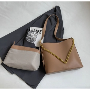 Detail of a brown leather tote bag with thick gold chain and matching inner pouch