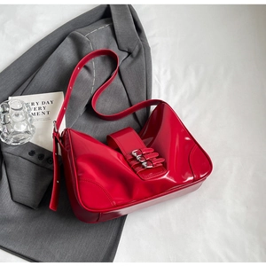 Detailed macro view of bright red patent leather handbag with silver buckle decorations