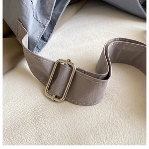 Macro detail of canvas strap with silver metal buckle and white stitching on bag