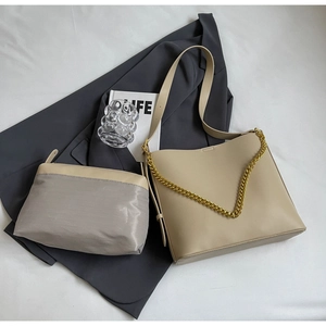 Detail of beige leather tote set with bold gold chain and grey mesh makeup pouch