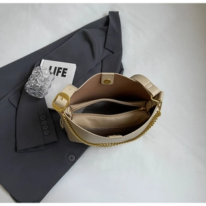 Detail view of beige tote bag with gold magnetic closure and chain strap detail