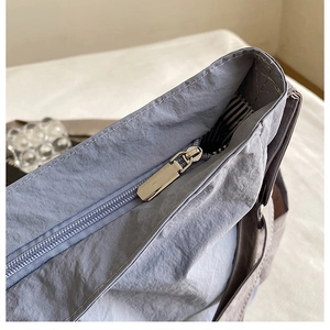 Close-up of durable nylon messenger bag featuring silver metal zipper and striped lining