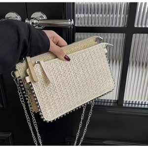 Detail of beige straw envelope bag with silver metallic bead trim and chain strap