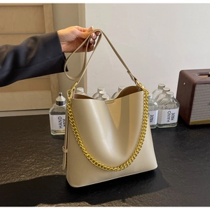 Close-up of beige tote bag with chunky gold chain detail and textured faux leather