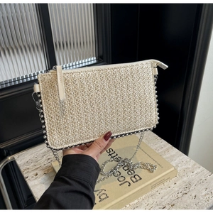 Detail of a woven straw envelope bag with silver bead trim and a thin metal chain strap