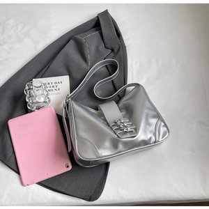 Detail view of silver metallic shoulder bag with decorative triple buckle straps on a blazer