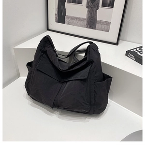 Macro view of black nylon hobo bag showing large flap pockets and functional side compartments