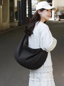 Black minimalist large nylon hobo shoulder bag shown in a stylish crossbody streetwear shot