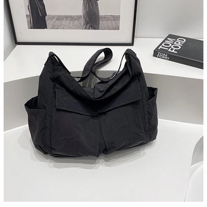 Detail view of black canvas crossbody bag with functional utility pockets on white steps