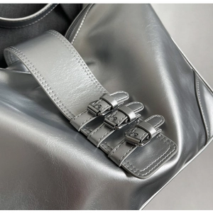 Detailed close-up of silver Y2K shoulder bag with triple buckles and metallic texture
