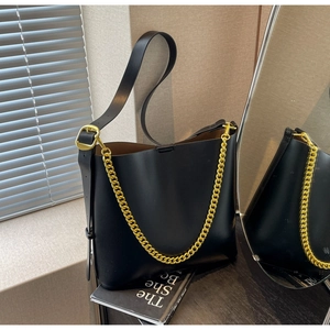 Detail of black matte leather bucket bag with gold chain strap and adjustable strap