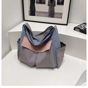 Detailed view of color-block canvas tote bag with multiple pockets on white steps