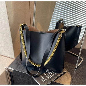 Detail of black leather tote bag with thick gold chain strap and chic matte finish