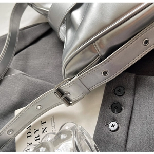 Close-up of metallic silver shoulder bag showing adjustable strap with metal eyelets