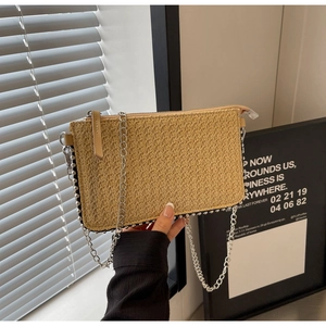 Detail of woven straw handbag featuring beaded edges and silver chain strap