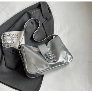 Detail of silver metallic underarm bag featuring triple buckle design and adjustable strap