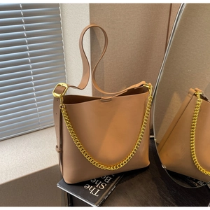 Detail of camel bucket bag featuring matte faux leather and gold chain strap accents