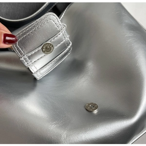 Close-up of the silver magnetic closure on a metallic textured underarm bag