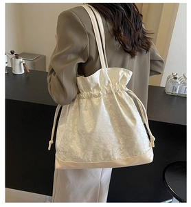Detail of floral jacquard satin tote bag with drawstring closure and leather base