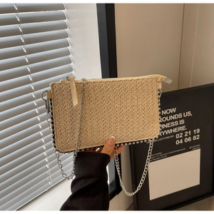 Detailed macro view of woven straw bag texture with metallic studs and silver chain strap
