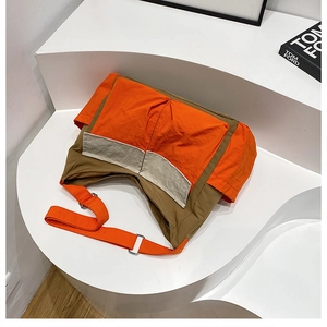 Detailed close-up of a two-tone nylon messenger bag in orange and brown with metal buckles