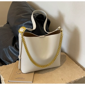 Detail of cream large tote bag featuring golden chain and adjustable wide shoulder strap