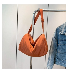 Detail van de karamel nylon halve maan tas met stoftextuur en de verstelbare schouderriem