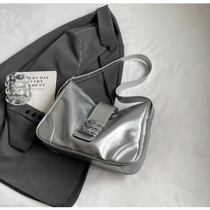 Close-up of metallic silver hobo bag with belt buckle detail on a grey suit jacket