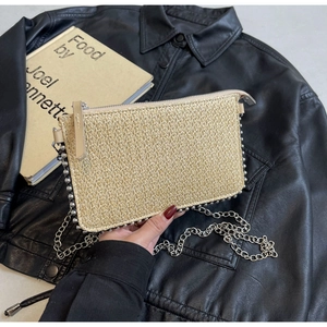 Detail of beige woven straw chain bag with silver beads on a black leather jacket