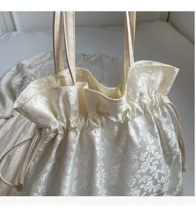 Detail of cream jacquard tote bag featuring floral patterns and leather handles