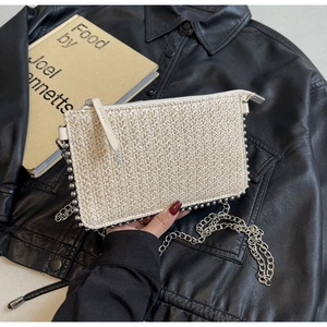Close-up of woven straw handbag with metallic bead trim and delicate silver chain strap