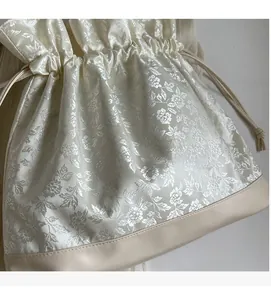 Detail of floral jacquard fabric and beige leather base on the drawstring bucket bag