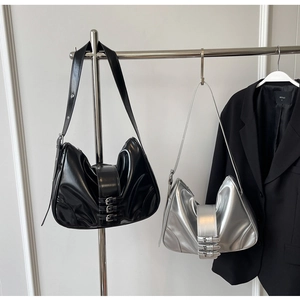 Close-up of retro hobo bags with shiny finish and decorative buckle belts on a metal rack