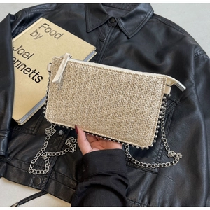 Detailed close-up of a beige woven crossbody bag with metallic bead trim and silver chain