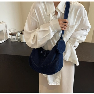 Detail of navy denim crescent crossbody bag with small round coin pouch and strap