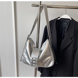 Detail of silver metallic underarm bag with three buckle straps and mirror finish texture