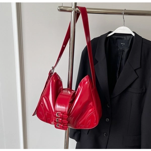 Detail of red patent leather shoulder bag with triple metal buckle straps in Y2K style