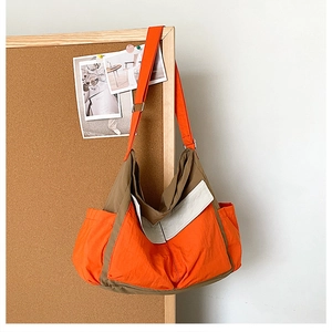Detail view of the orange and brown contrast stitching nylon canvas crossbody bag