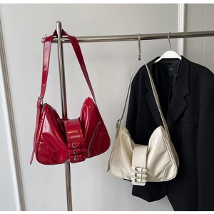 Detail view of red and cream patent leather shoulder bags with triple buckle straps