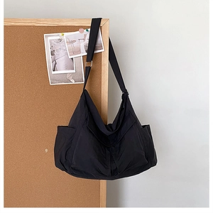 Detail of adjustable metal buckle and wide strap on black canvas messenger bag