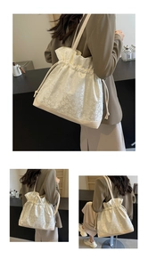 Detailed view of white drawstring tote bag featuring floral jacquard and leather base